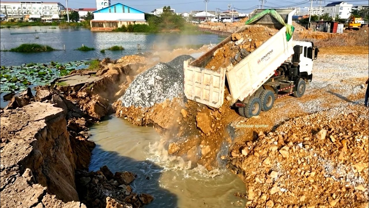 Great work dump truck wheel 10 unloading stone landfill flooded & bulldozer DH17 working push soil.