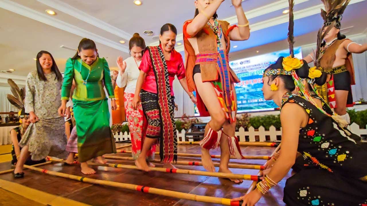 Tourists trying out the Bamboo Dance of Sabah