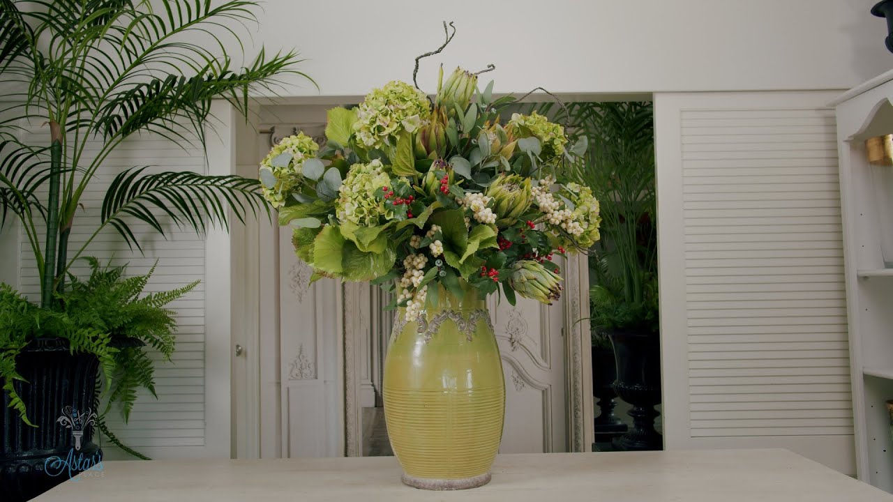 Relaxed, informal floral design of green hydrangeas, proteas, eucalyptus, holly & snow berries