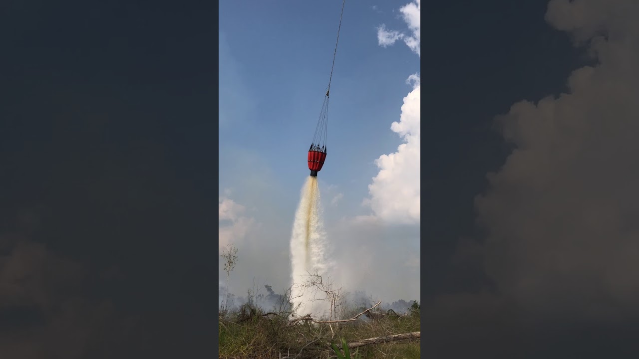 Fire fighting helicopter douses peat fire blaze outside village of Kemang in Riau