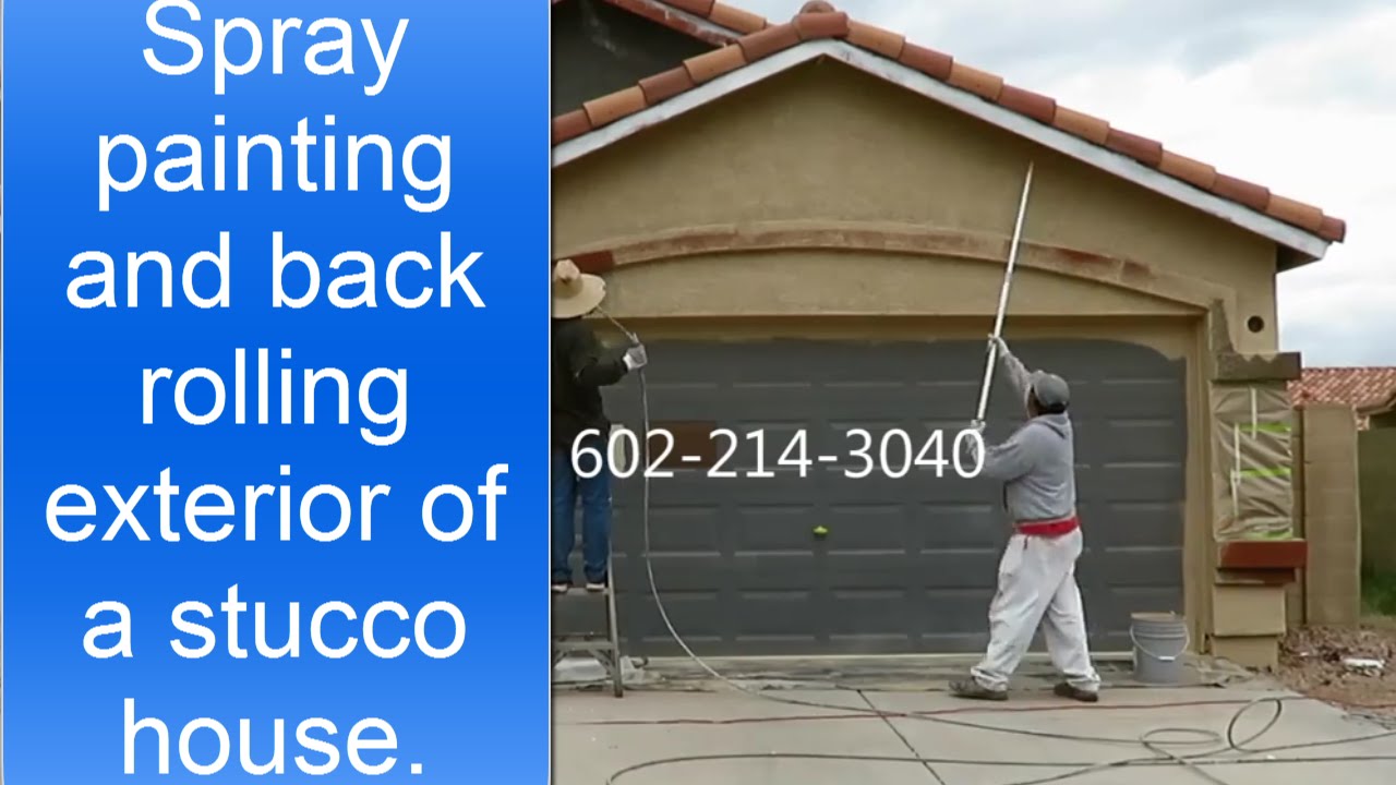 Spray painting and back rolling exterior of a stucco house.
