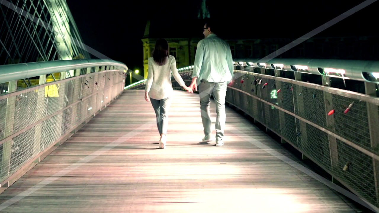 couple walking holding hands on bridge in the night 4yWUAK47e
