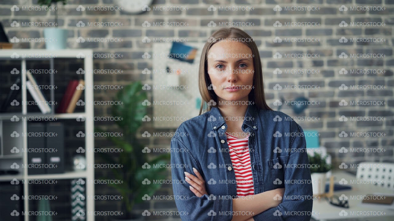 Portrait of good-looking young woman standing in office with arms crossed