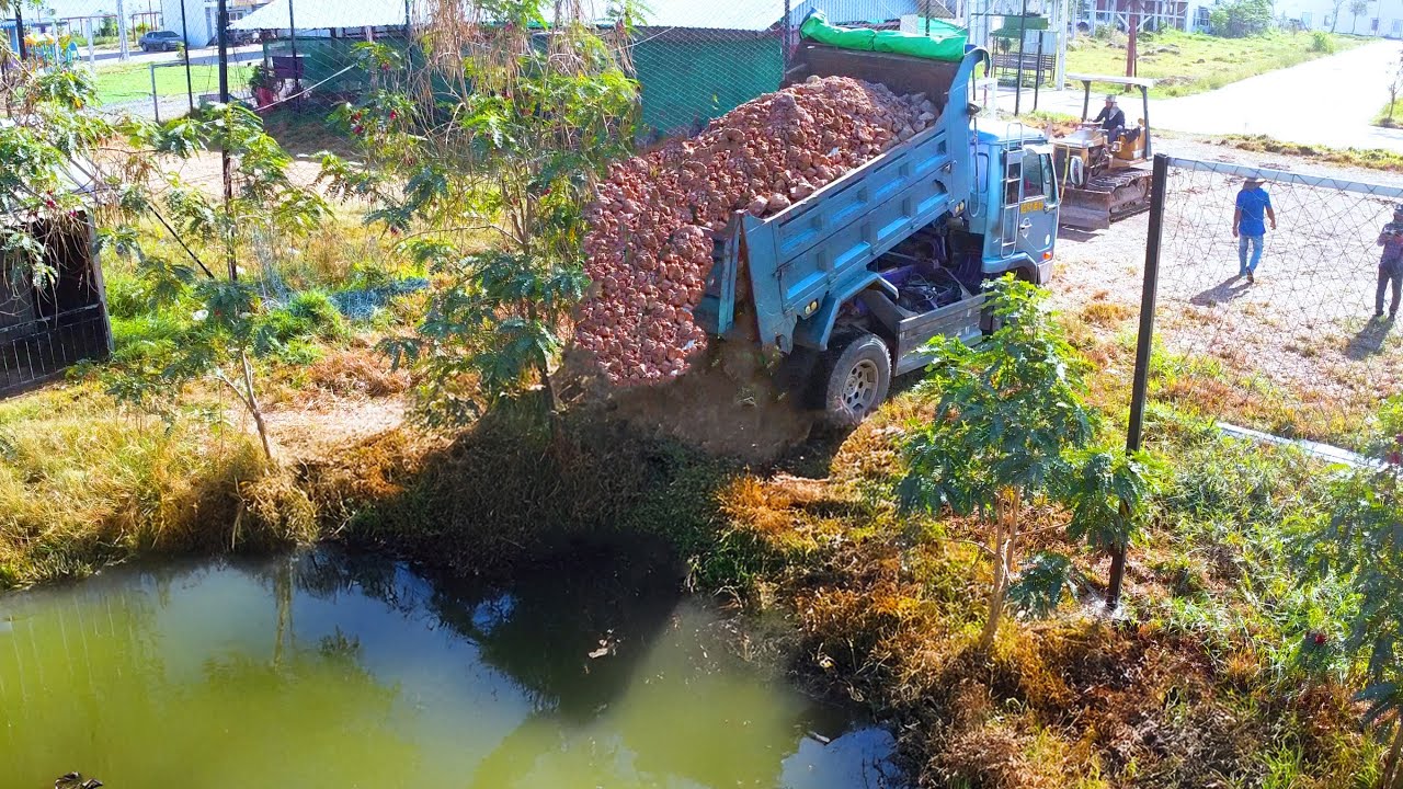 First truck unload bulldozer bushing soil for filling pond and fight tree for building new road