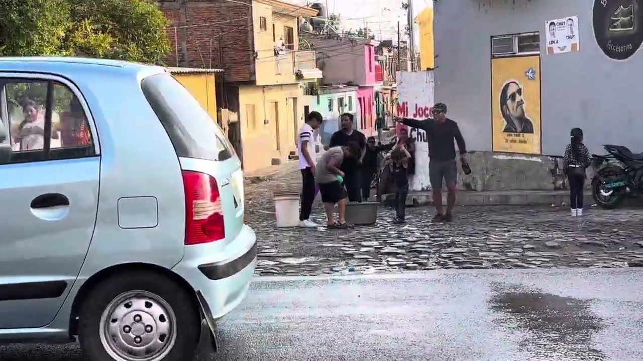 SAN JUAN COSALA-2024 -ON THE CARRETERA -PEOPLE HAVING FUN SPLASHING WATER ON OTHERS ON HOT DAY  