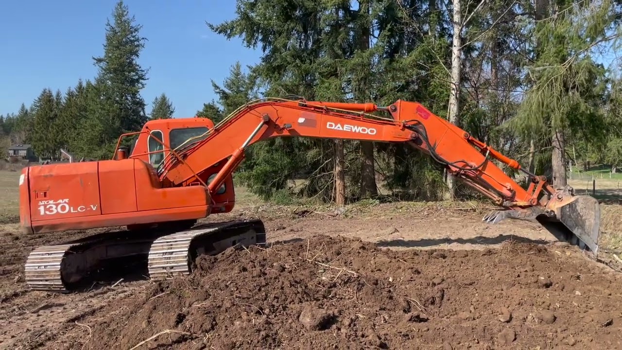 Daewoo 130 Grading dirt and loading brush