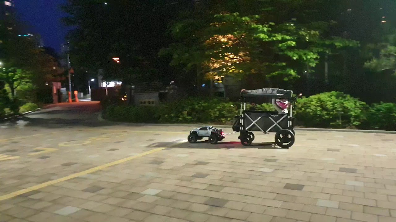 Traxxas xmaxx tows a wagon(stroller) a child is riding.