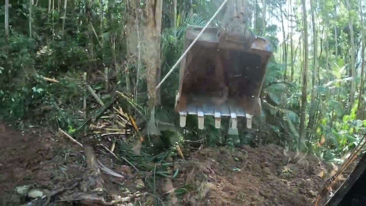 Escavadeira abrindo estrada com deslizamentos