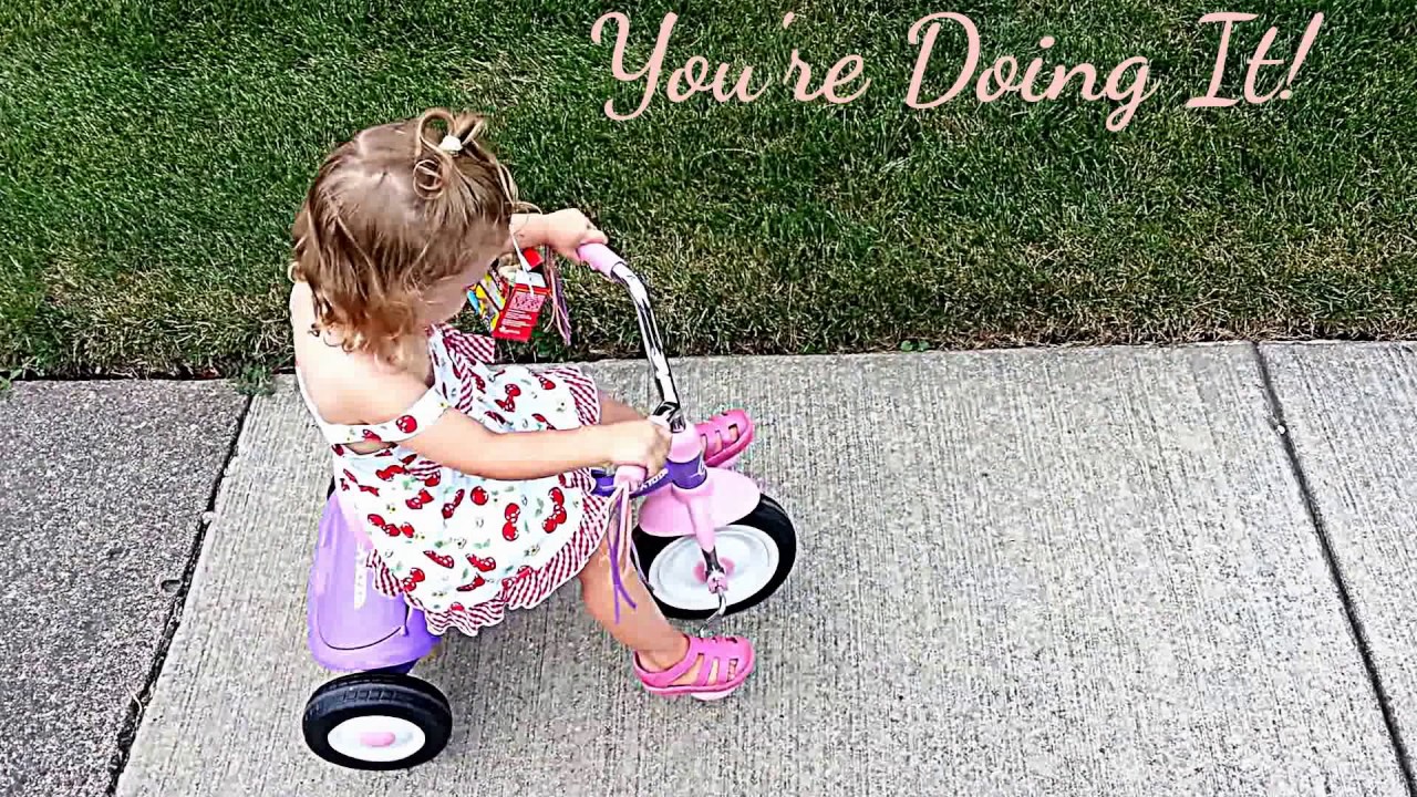 A toddler is learning how to ride a tricycle!