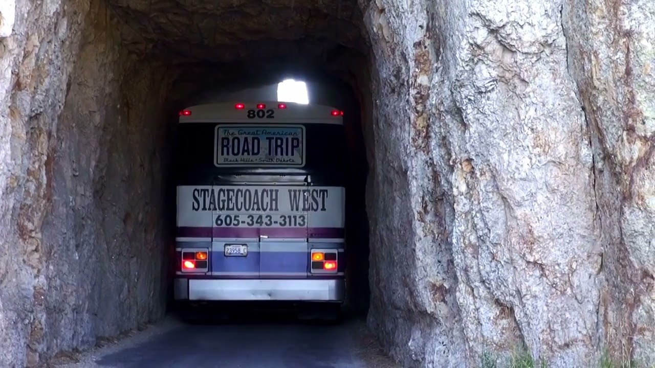 Bus drives through the Needles Highway tunnel - 8 feet wide Needles Eye Tunnel in South Dakota