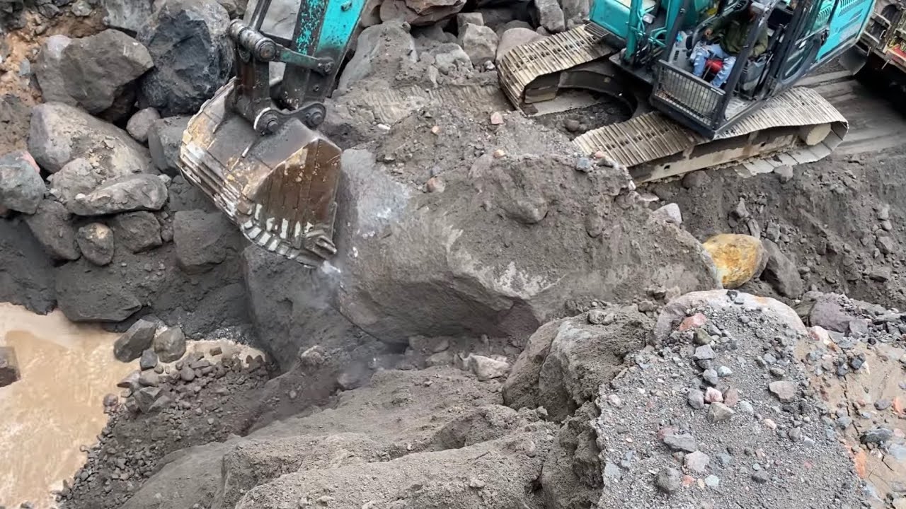 Heavy equipment works in sand mining, breaking down large rocks