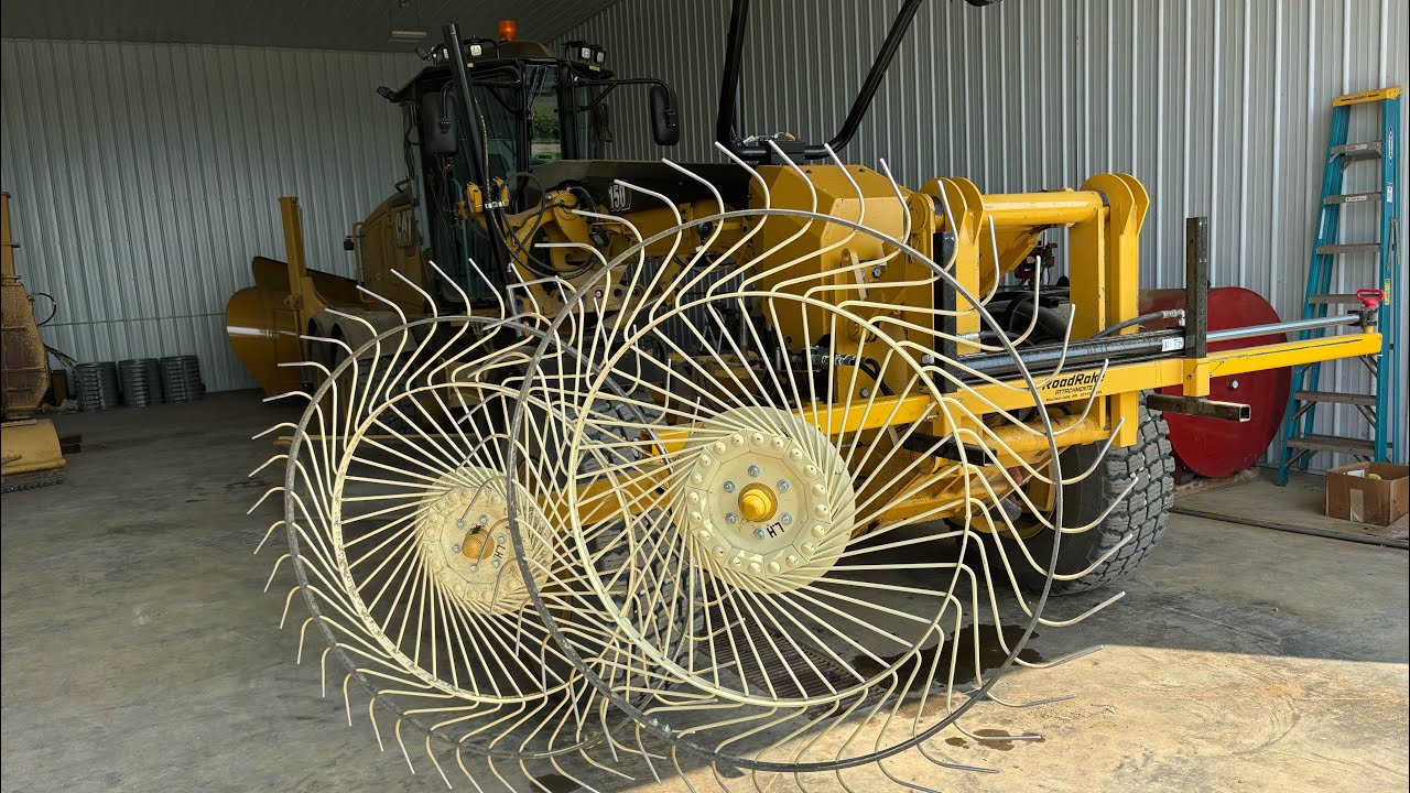 Cat 150 grading roads with front mount hay rake