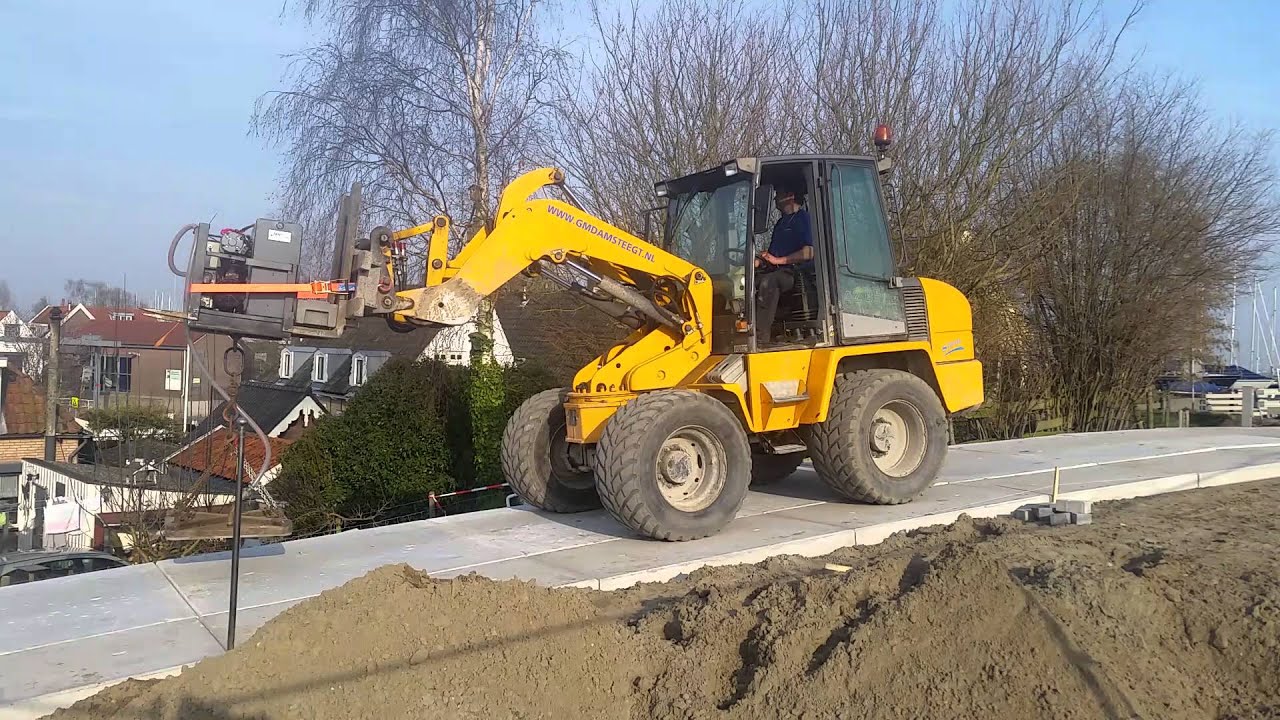 G.M. Damsteegt met een AZ 85 ahlmann & elektrisch vacuum unit zware beton platen leggen