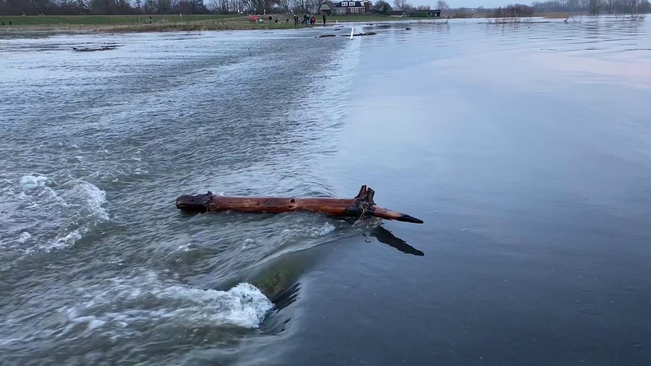 Hoogwater IJssel stroomt over asfaltweg in uiterwaarden