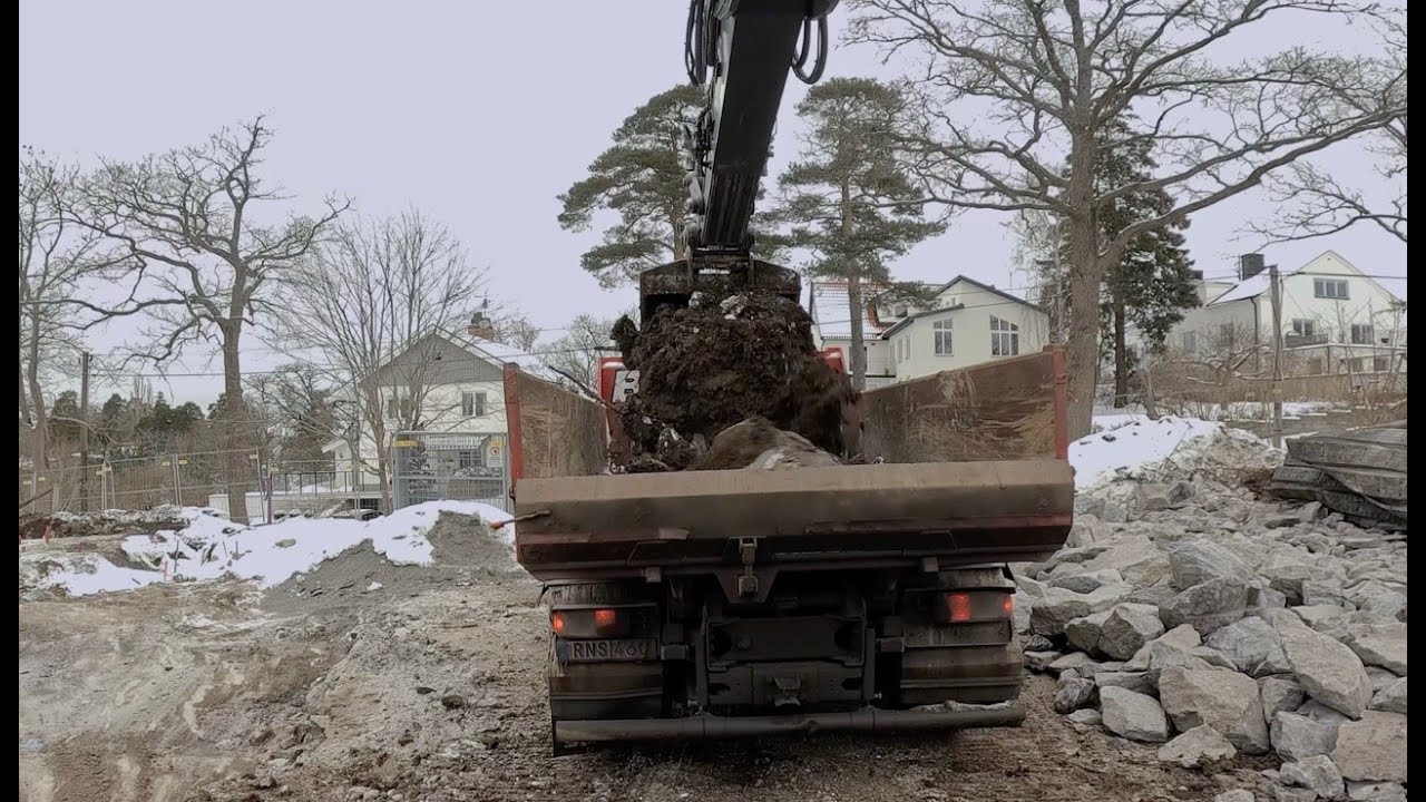 Excavator loading trucks and fighting rocks