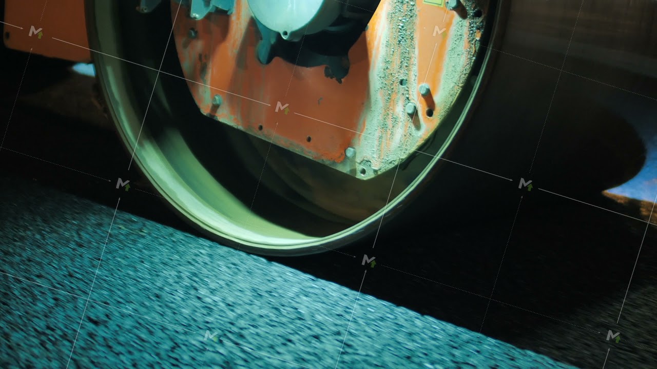 Close-up of a road roller drum. Night time. Road construction equipment. Road surface repair
