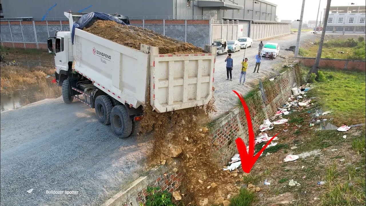 heavy dump truck wheel 10 unloading soil landfilling up flooded areas and SHANTUI bulldozer pushing 