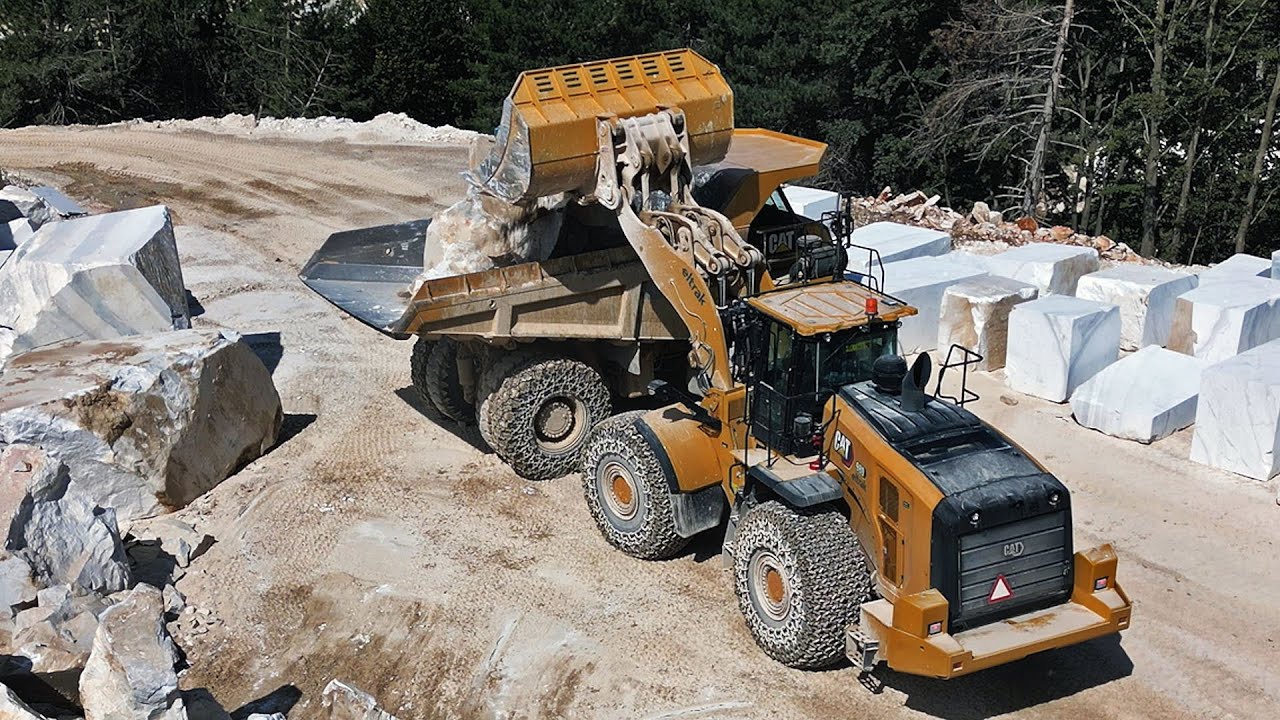 CAT 980 wheel loader loading CAT 770 dump truck in marble quarry.