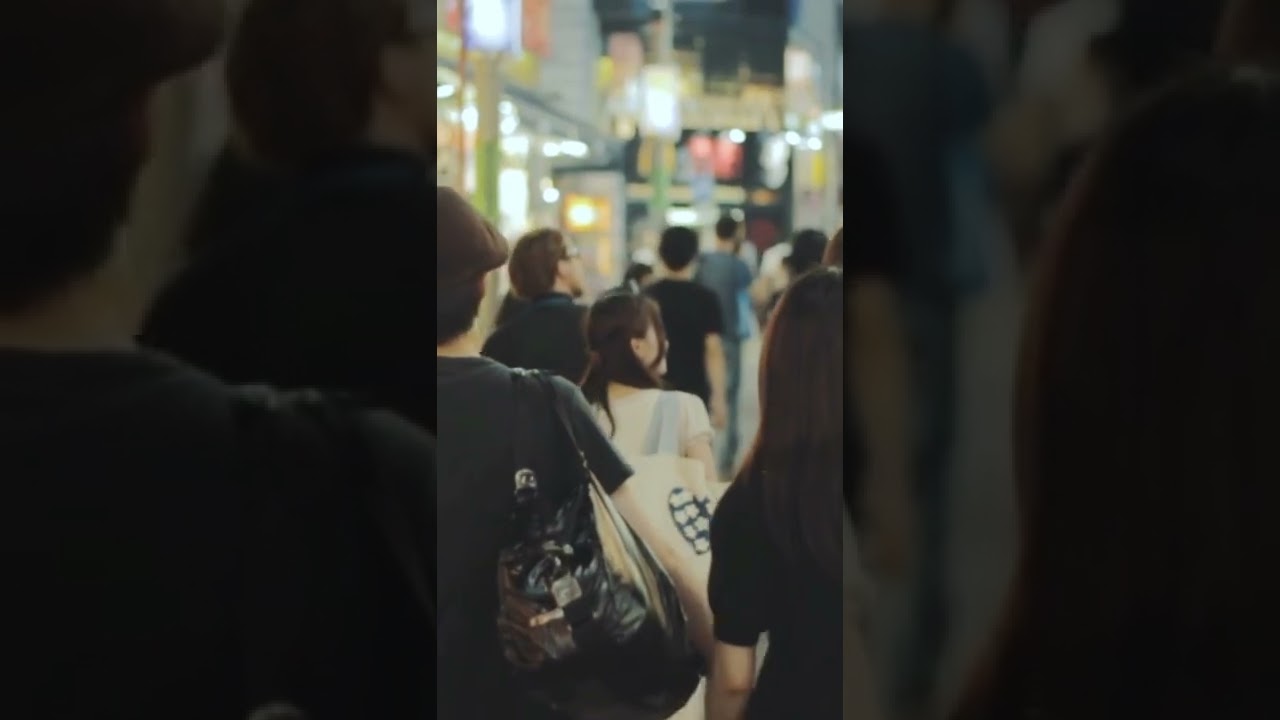 Couple Holding Hands While Walking on a Busy Street