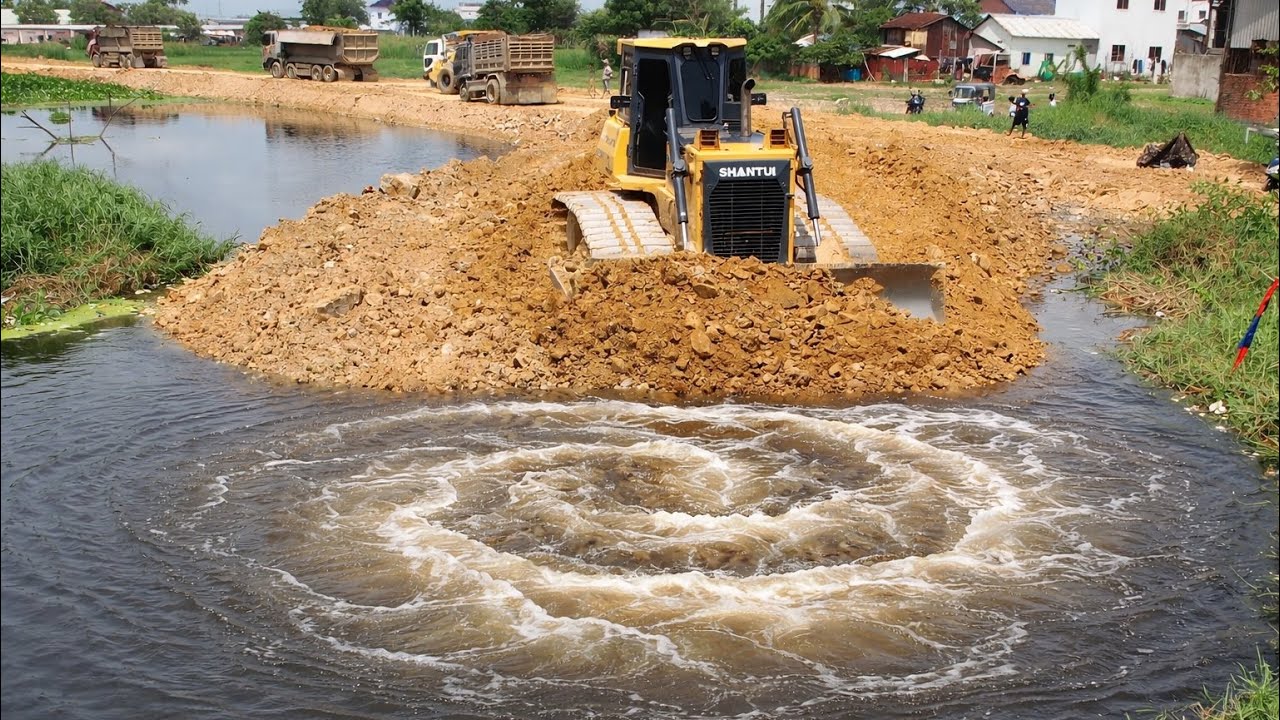 Interesting SHANTUI Bulldozer Making a Road in flooding area with Dump Trucks loading soils 