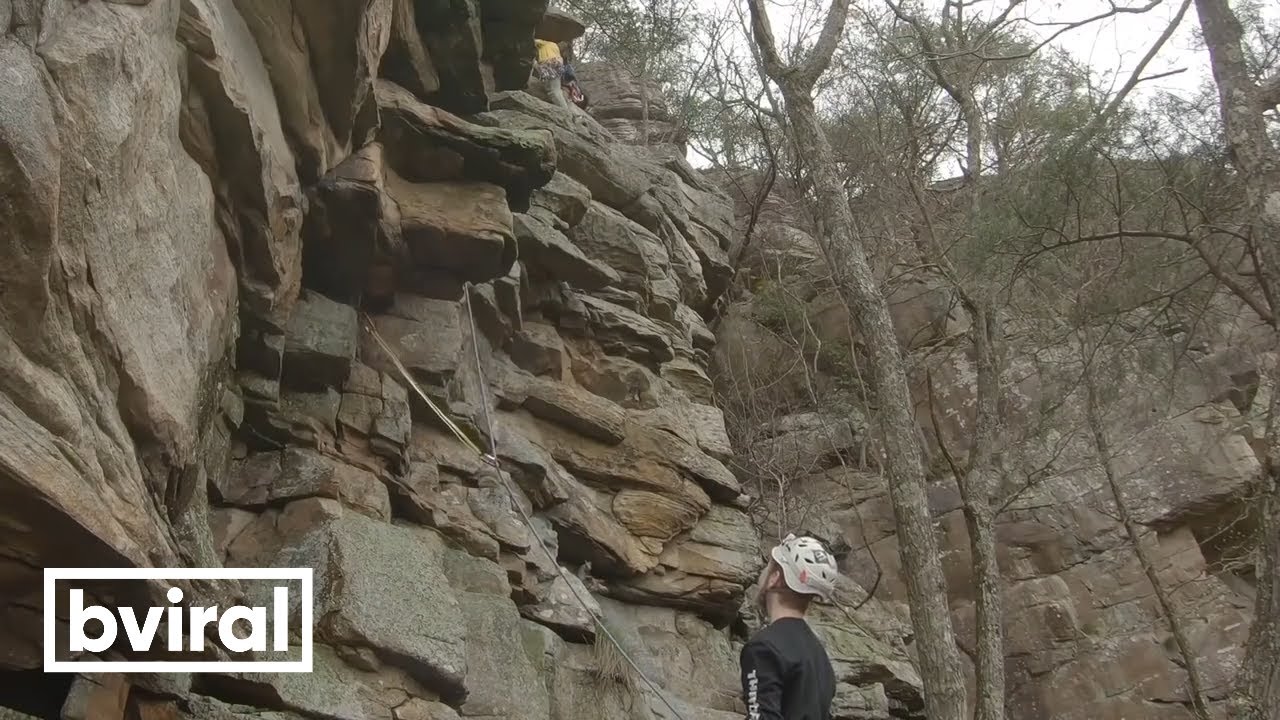 Climber, wearing a helmet, gets hit on the head with a rock.