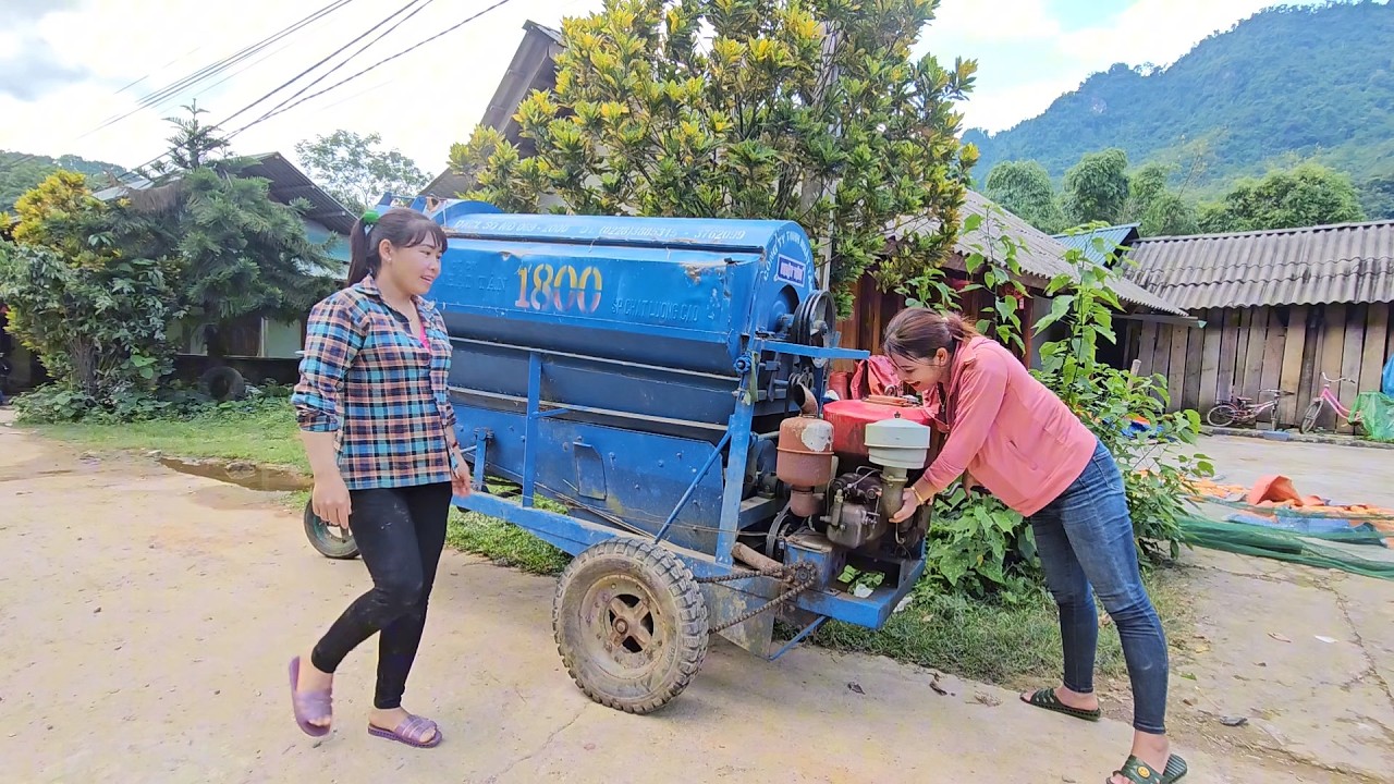 Two girls operate a machine to help the villagers thresh their rice.