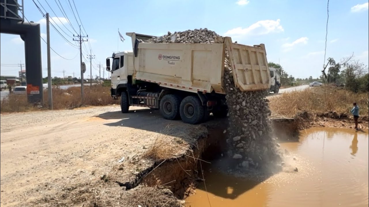 Dump truck wheel 10 unloading stone landfill building Road with Dozer SHANTUI DH17C3 Pro pushing 
