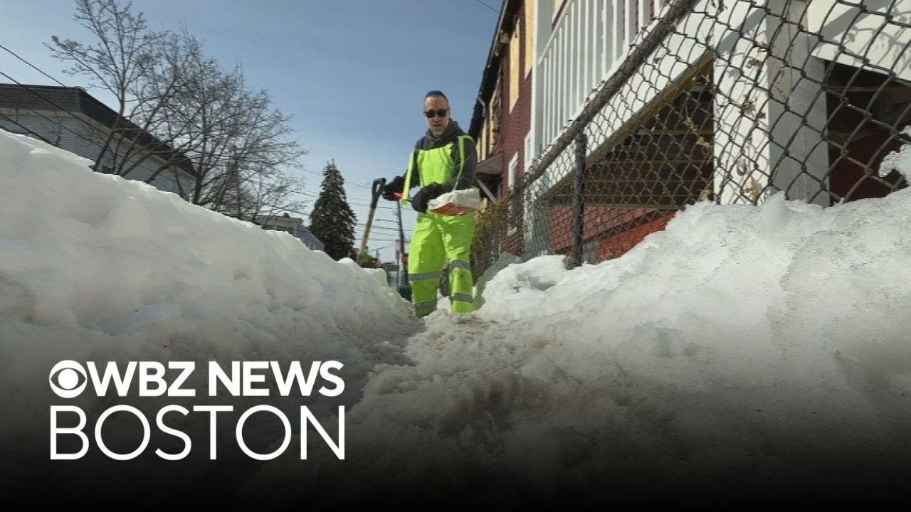 Somerville man works to clear sidewalk buried in snow after fire