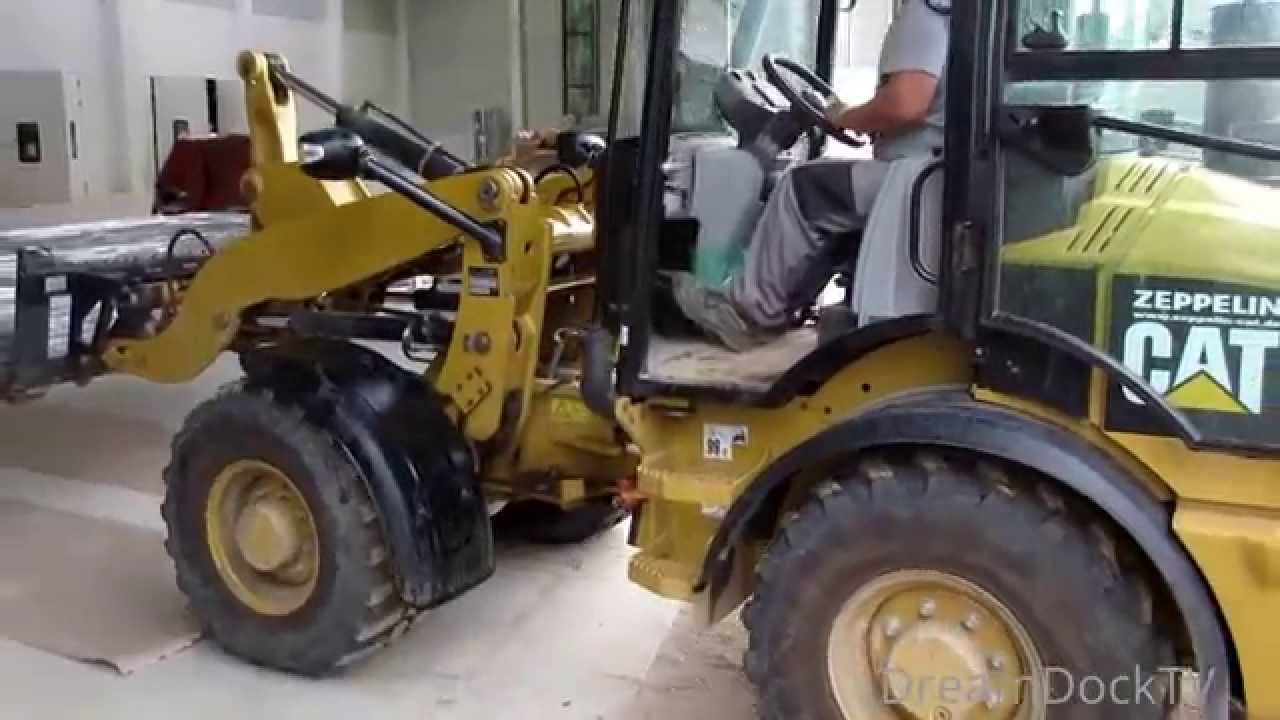WHEEL LOADER CATERPILLAR 907H WORKING ON CONSTRUCTION SITE WITH BUCKET & FORK
