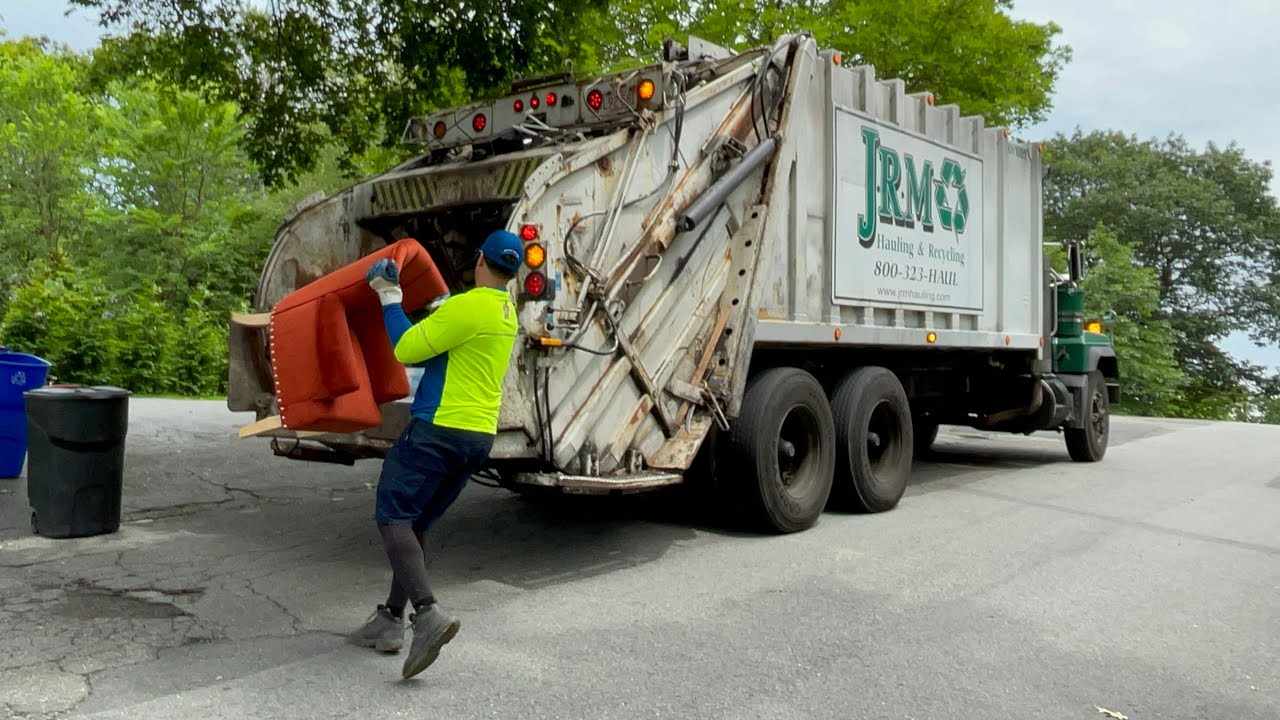 Old roaring JRM garbage truck packing heavy hillside trash