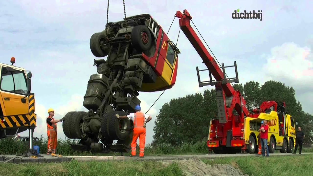 Vrachtwagen met asfalt op de kop in sloot