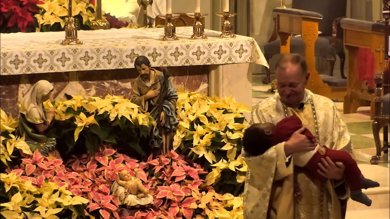 Priest Holds Baby during Christmas Homily, Holding the True Meaning of Christmas
