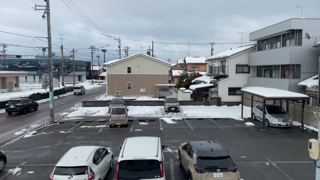 A Snow-covered Field, Road, Buildings, and Houses Beyond - Komatsu, Japan - January 27, 2026