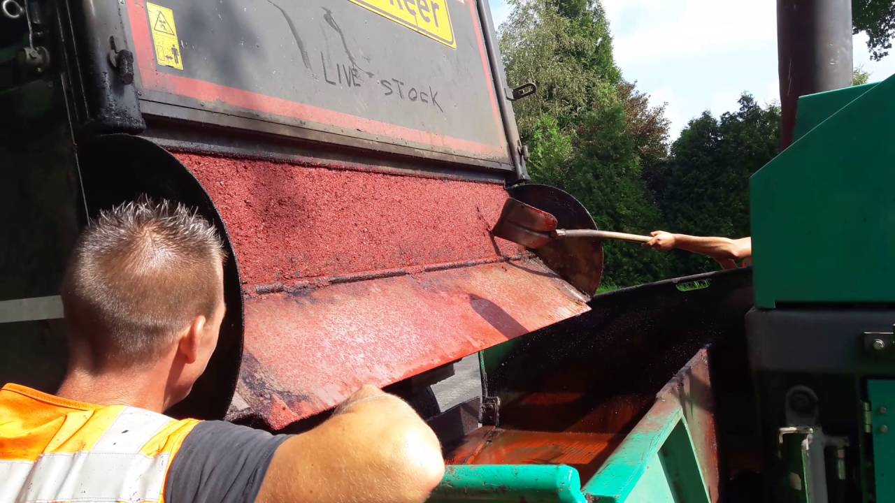 de vrachtwagen leegd de bak met rood asfalt