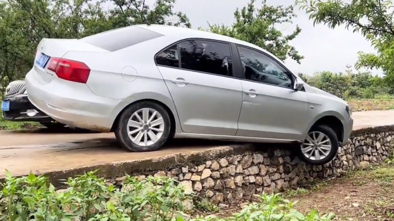 When Two Vehicles Meet, One Reverses And Falls Off The Curb.