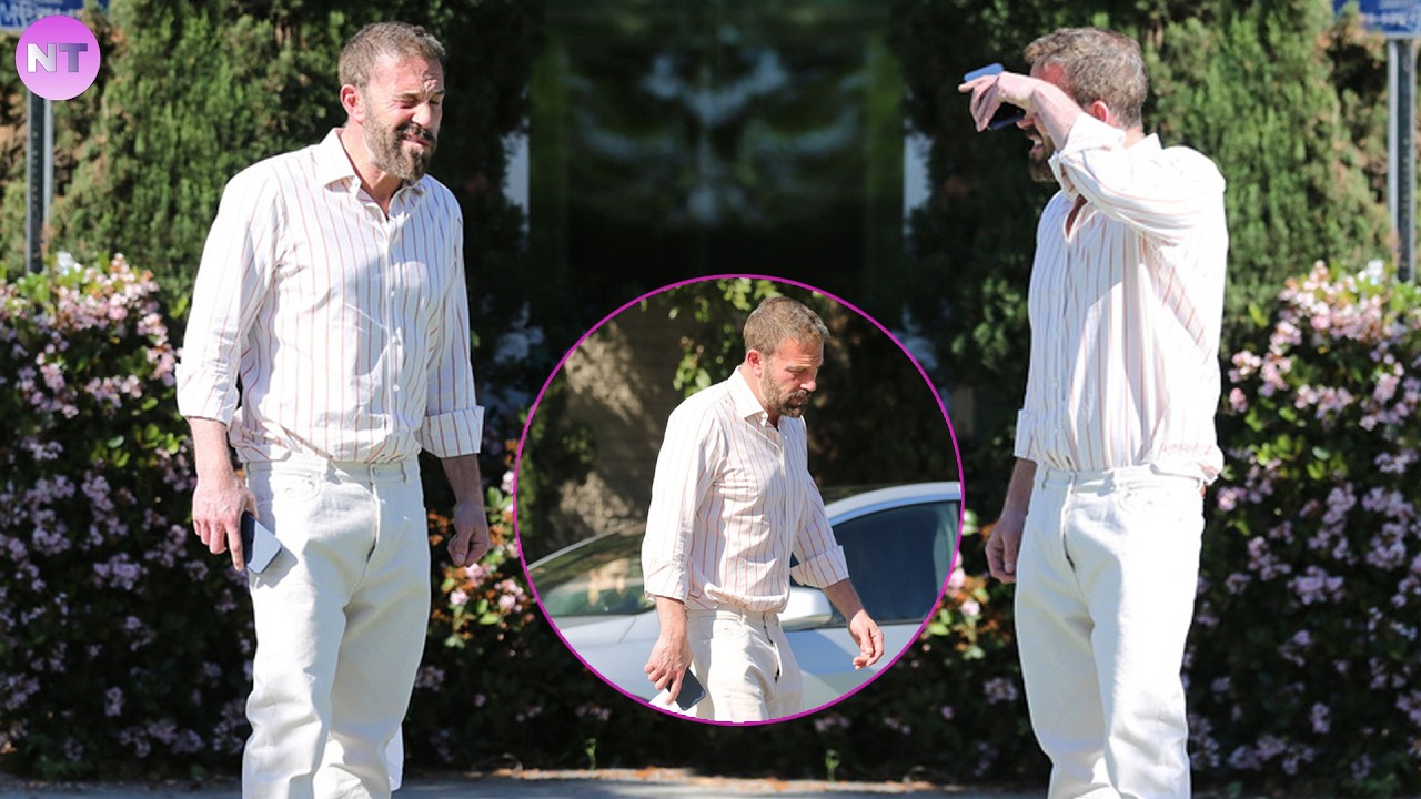 Ben Affleck strolls leisurely along a path lined flowering shrubs after taking his son for a walk