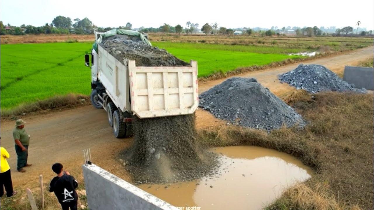 Wonderful heavy dump truck unloading soil landfilling flooded with SHANTUI bulldozer working push 