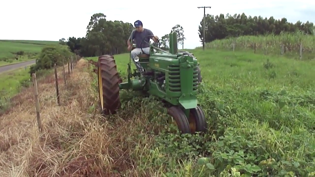 Trator antigo John Deere 1952 arando terra
