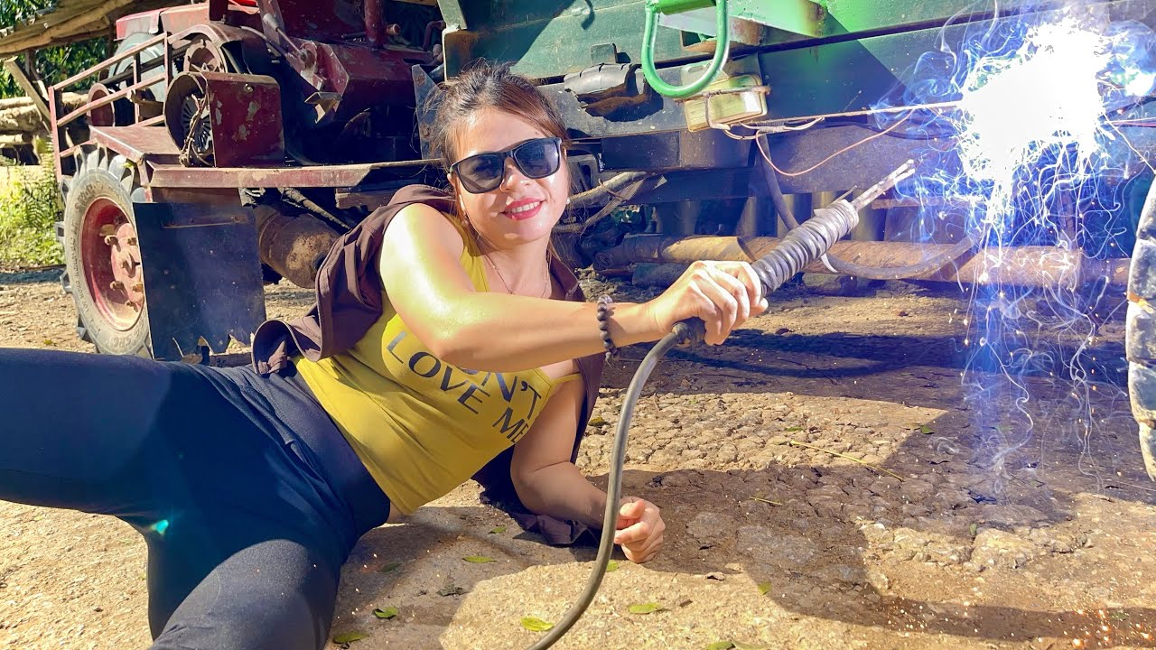 Talented female mechanic: welding the outer column of a tractor for a customer