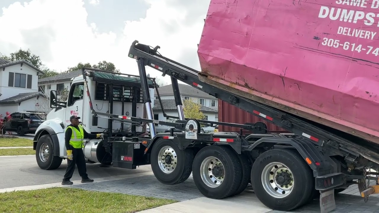 A USA Dumpster Premier roll off dropping off pink dumpster 