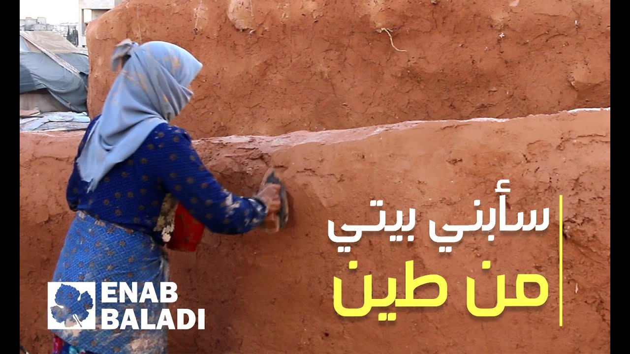 امرأة تبني بيتًا من الطين لأولادها في مخيمات ريف إدلب
