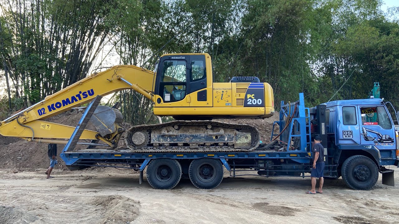 Self-Loader Trucks Transporting Komatsu PC200 Excavator to the garage