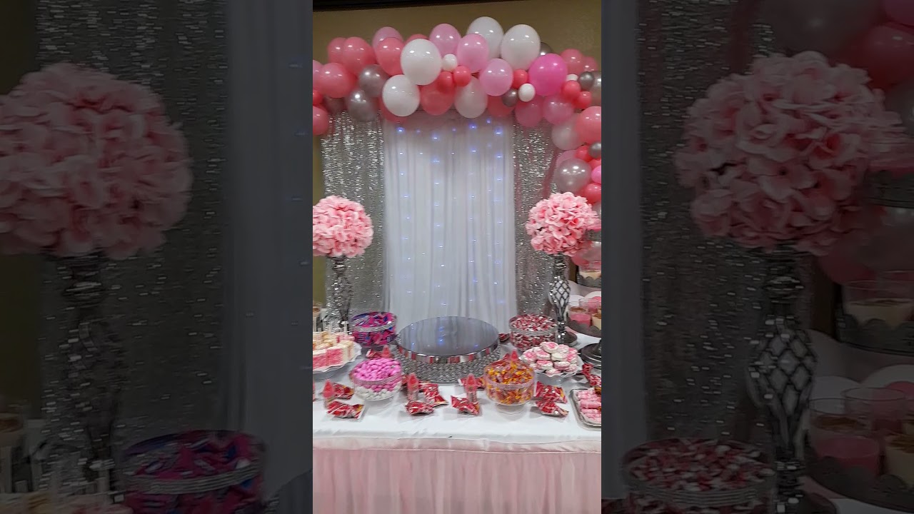 Baby shower decoration pink and silver balloons arch and string lights backdrop with candy table
