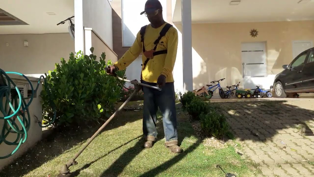 Eu estou mostrando o meu irmão roçando a grama esmeralda e limpo