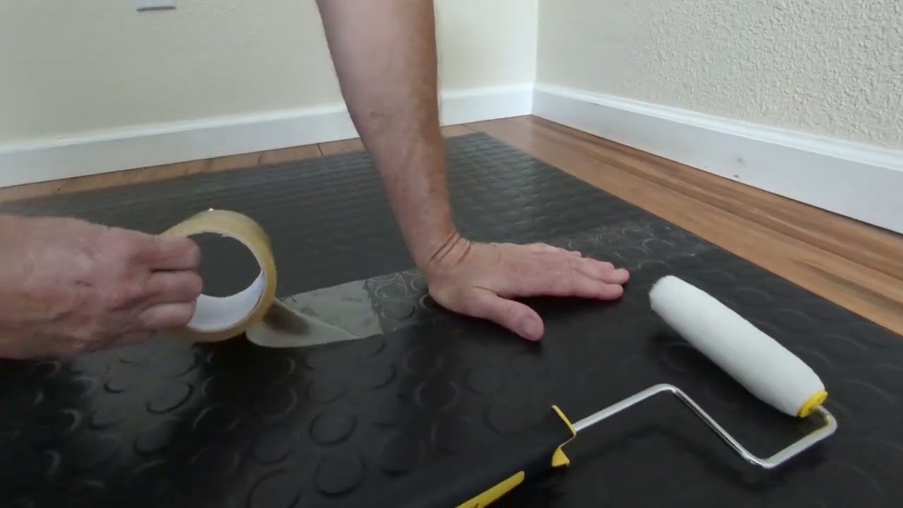 Applying gym mat tape to home gym rubber floor tiles