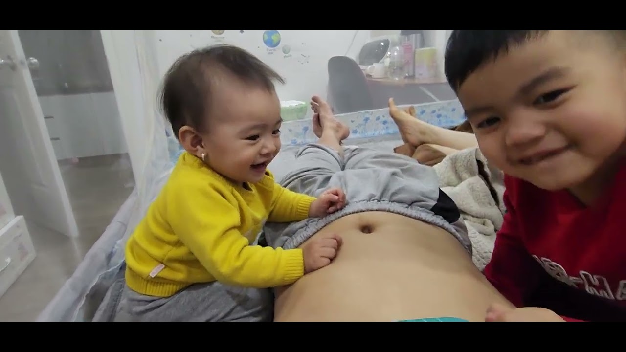 2 anh em chơi trên bụng bố