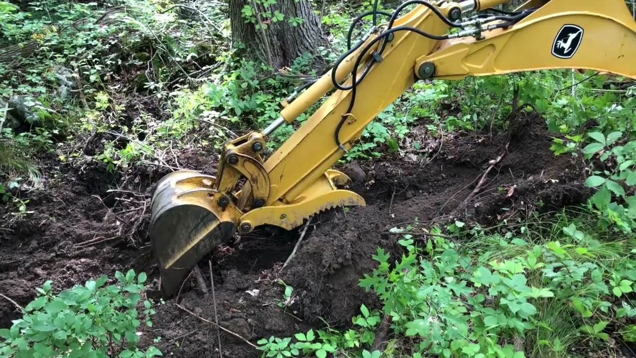 John Deere 110 TLB opens a drainage ditch