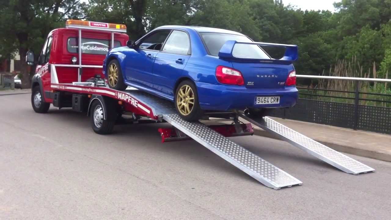 Cami&oacute;n gr&uacute;a plataforma Thalman en Aluminio de Mapfre cargando y descargando un Subaru Impreza.