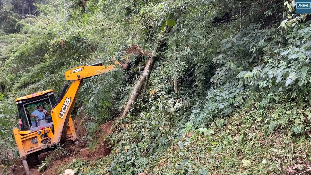 In a Winter Cold and Foggy Day Making Narrow Mountain Road with JCB Backhoe