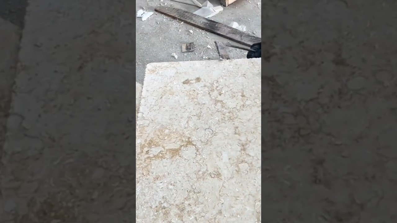smoothing a large beige marble stone slab precisely using a small manual metal tool